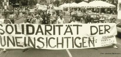 schwarz-weißes Demo-Foto mit Banner "Solidarität der Uneinsichtigen"