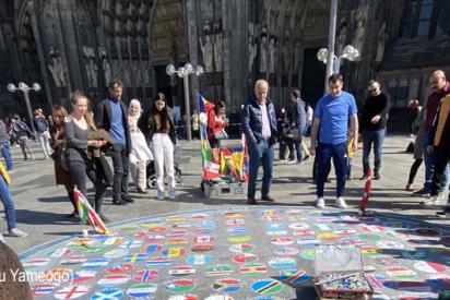 Menschen vor auf dem Boden gemalte Flaggen