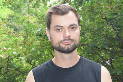 Porträt von Borys Hrachov im schwarzen Top vor grünen Bäumen