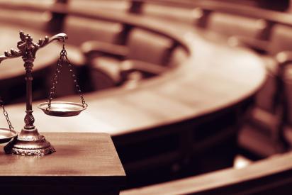 Leerer Gerichtssaal, im Vordergrund Waage der Justitia