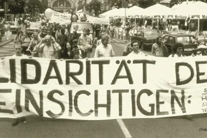 schwarz-weißes Demo-Foto mit Banner "Solidarität der Uneinsichtigen"